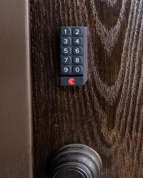 A close-up of a keypad with numbers 1-9 on a wooden door next to a round doorknob.