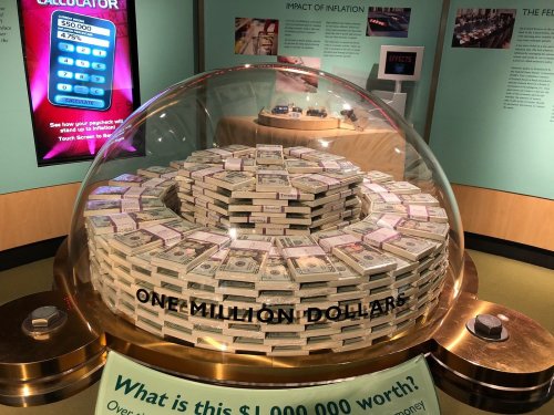 A display featuring a dome of stacked cash, showcasing one million dollars in a museum exhibit about money.