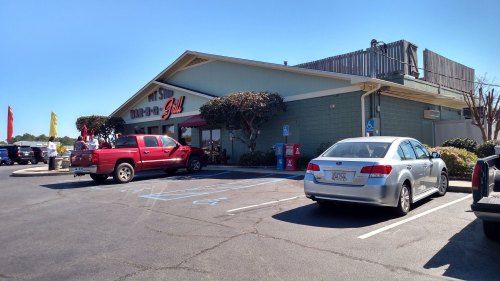 A red pickup truck and a silver sedan parked outside a restaurant with a sign reading "Bar-B-Q Grill."