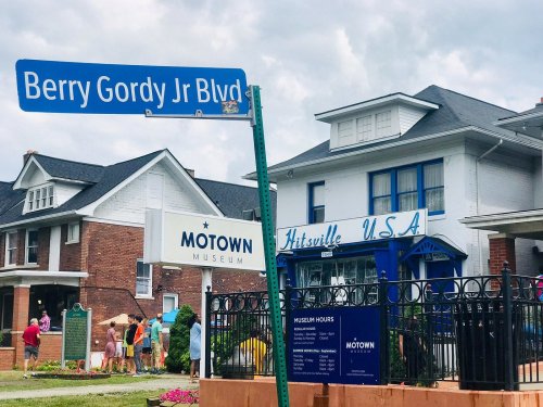Sign for Berry Gordy Jr Blvd in front of the Motown Museum and Hitsville U.S.A. with visitors in the background.