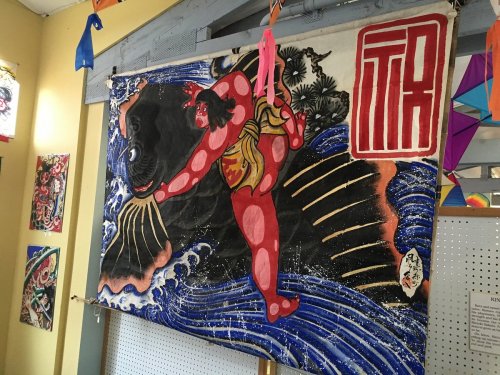 A colorful mural depicting a figure in traditional attire against a dark, swirling background, with decorative elements.