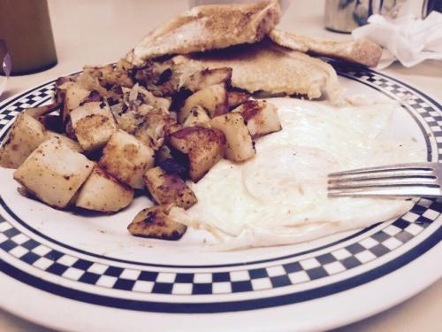 A plate of breakfast featuring fried eggs, seasoned potatoes, and toast on a checkered plate.