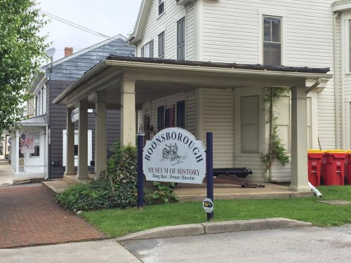 Sign for Boonsborough Museum of History, with a porch and nearby buildings, set in a small town.