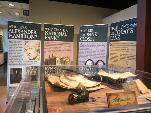 Exhibit featuring panels about Alexander Hamilton and banking history, with a display case holding historical documents.