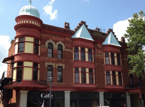 Historic red brick building with ornate architecture, featuring large windows and a green domed roof.