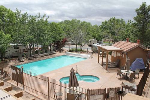 A view of a swimming pool surrounded by trees, with lounge chairs and a hot tub nearby.
