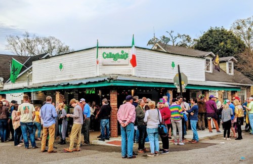 A lively crowd gathers outside Callaghan's Irish Pub, with festive decorations and a mix of people enjoying the atmosphere.