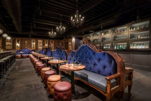 Elegant restaurant interior featuring plush blue seating, wooden tables, and stylish chandeliers.