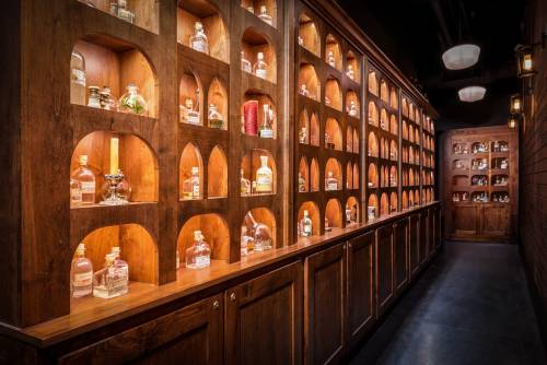 A wooden display with illuminated shelves showcasing various bottles in a dimly lit, elegant setting.