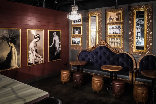 Cozy restaurant corner with vintage photos, elegant mirrors, and plush seating against a dark wood backdrop.