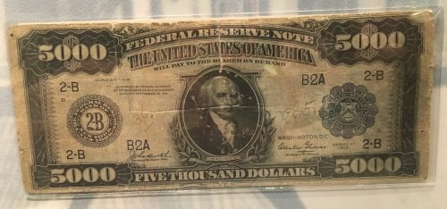 A vintage $5,000 Federal Reserve note featuring a portrait of a historical figure and intricate designs.