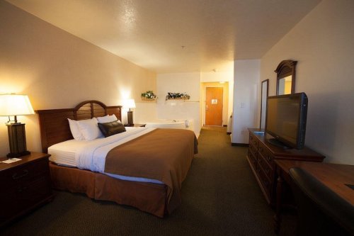 A cozy hotel room featuring a king-sized bed, a TV, and a seating area with warm lighting and neutral decor.