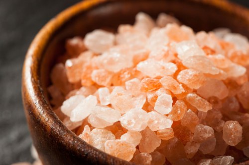 Close-up of pink Himalayan salt crystals in a wooden bowl.