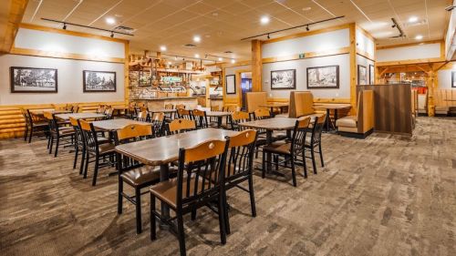 Interior of a cozy restaurant with wooden decor, empty tables, and a warm, inviting atmosphere.