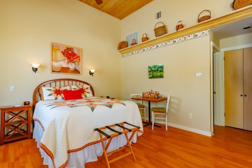 Cozy bedroom with a quilted bed, wooden furniture, and warm lighting, featuring a small dining table and decorative baskets.