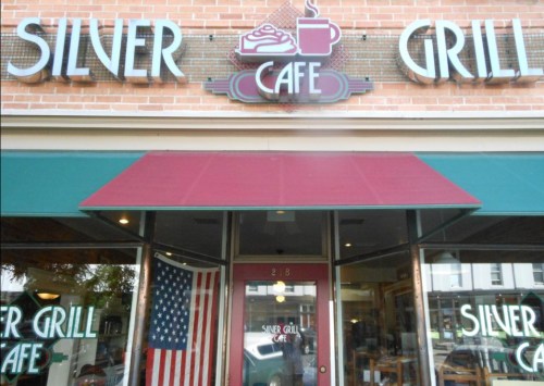 Exterior of Silver Grill Cafe, featuring a red awning and an American flag, with a vintage sign above the entrance.