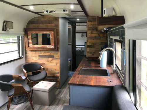 Interior of a modern camper van featuring wooden accents, a kitchenette, seating area, and cozy decor.