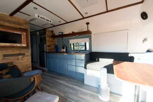 Interior of a modern, cozy camper van featuring a kitchen area, seating, and wooden accents. Bright and inviting space.