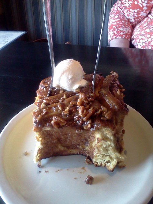 A slice of pecan pie topped with a scoop of ice cream and two forks, served on a white plate.