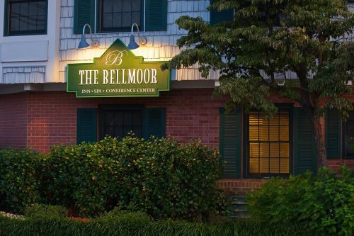 Sign for "The Belmoor Inn & Conference Center" illuminated at night, surrounded by greenery and brick architecture.