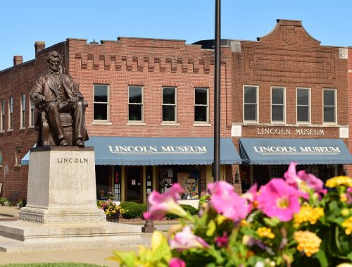 Statue of Abraham Lincoln in front of the Lincoln Museum, with colorful flowers in the foreground.