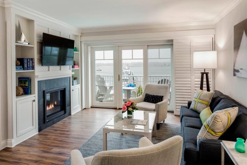 Cozy living room with a fireplace, TV, and views of the water through sliding glass doors. Modern decor and furniture.
