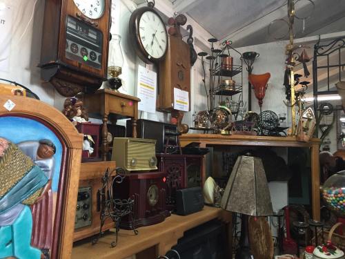A collection of vintage items, including clocks, radios, and decorative pieces, displayed on wooden shelves.