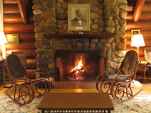 Cozy living room with a stone fireplace, two rocking chairs, and warm lighting, creating a welcoming atmosphere.