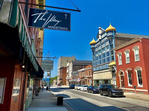 A sunny street scene featuring colorful buildings, shops, and clear blue skies.