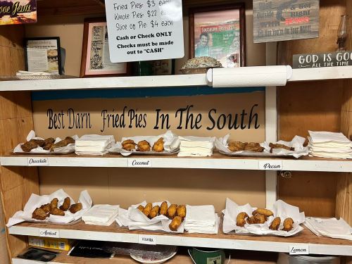 A display of various fried pies labeled by flavor, with prices and a sign reading "Best Darn Fried Pies In The South."