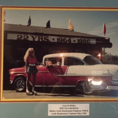 A woman on roller skates poses by a 1955 Chevrolet Bel Air outside a diner celebrating 22 years in business.