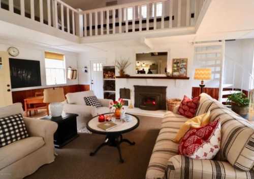 Cozy living room with a fireplace, comfortable seating, and a lofted area, featuring warm decor and natural light.