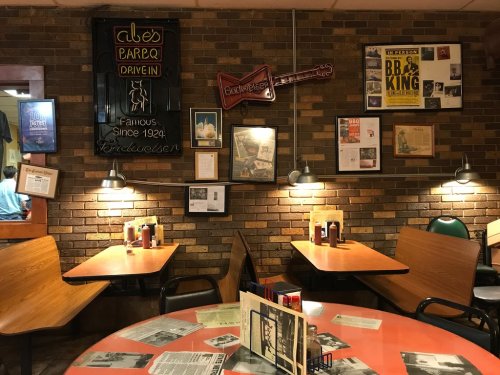 Cozy diner interior with brick walls, wooden tables, and vintage decor, including music memorabilia and menus.
