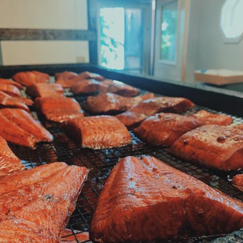Smoked salmon fillets arranged on a grill, with a bright window in the background.