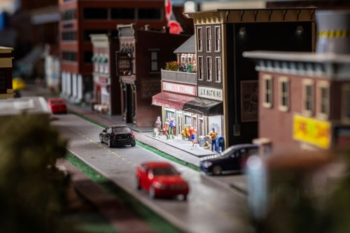 A detailed miniature street scene with shops, cars, and people, showcasing vibrant urban life in a model setting.