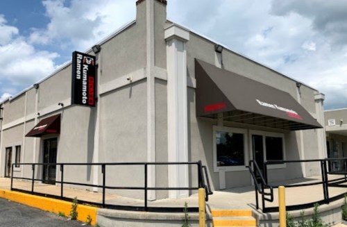Exterior of a commercial building with a sign for "Renton" and awnings, featuring a ramp and yellow curb.