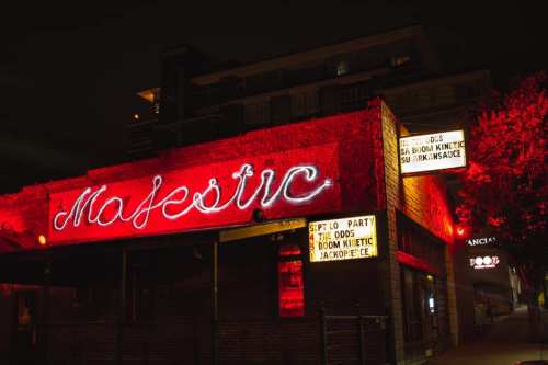 A nighttime view of the Majestic venue, illuminated by red neon lights and featuring event signage.