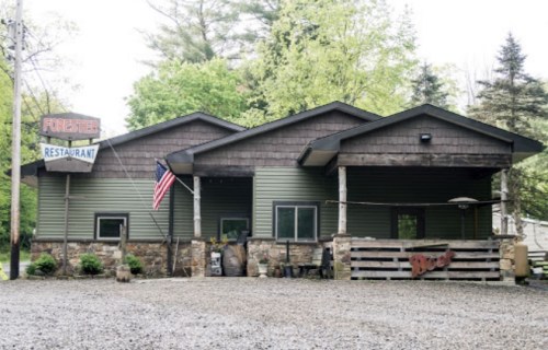 A rustic restaurant building with a stone facade, an American flag, and a sign reading "Forester Restaurant."