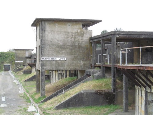 Abandoned concrete military structures with a sign reading "Meriwether Lewis" in a grassy area.