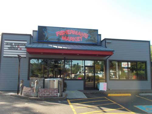 Exterior of Fisherman's Market, featuring a sign and large windows, with a parking area in front.