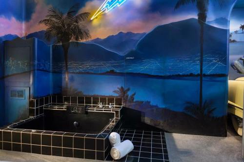 A modern bathroom featuring a black tub, palm tree mural, and neon lighting against a scenic mountain backdrop.
