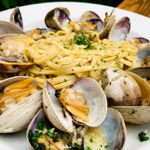 A plate of linguine with clams, garnished with parsley and served in a white bowl.