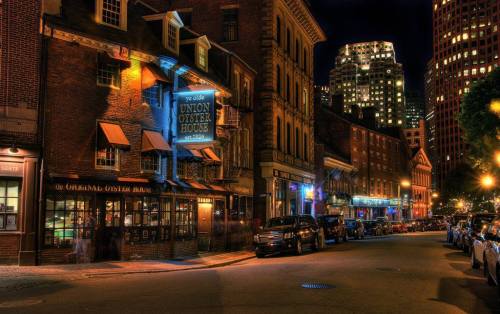 Historic Union Oyster House illuminated at night, surrounded by brick buildings and city lights.