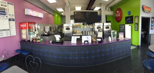 Brightly colored ice cream shop interior with a service counter, soda machines, and menu boards.
