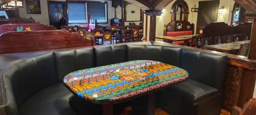 A colorful, intricately designed table in a cozy restaurant booth with wooden decor and seating.