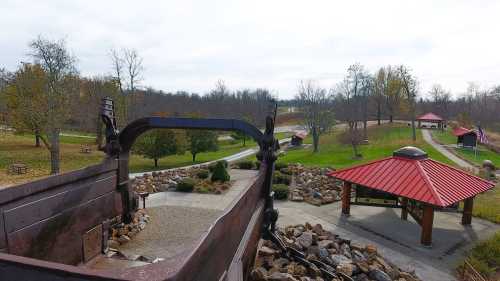 A view from above showing a park with a red-roofed pavilion, pathways, and trees in the background.