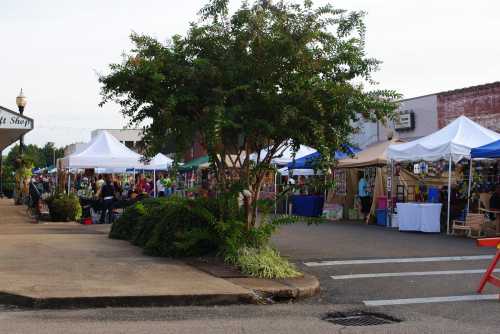 A vibrant outdoor market with colorful tents, vendors, and shoppers in a lively street setting.