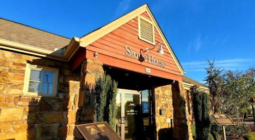 Exterior of a stone building with a wooden sign reading "Store House" under a clear blue sky.