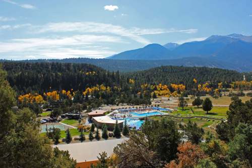 A scenic view of a pool area surrounded by trees and mountains, with autumn colors in the landscape.