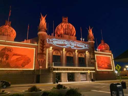 The brightly lit exterior of the World's Only Corn Palace at night, featuring unique architectural designs and decorations.